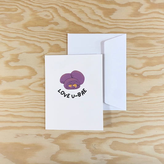 A white card with a white envelope. Three purple ube buns are displayed with custard seeping out of one. The words "love u-bae" are written along the bottom of the three buns.